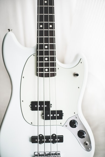 白色表面上的白色和黑色电低音吉他
